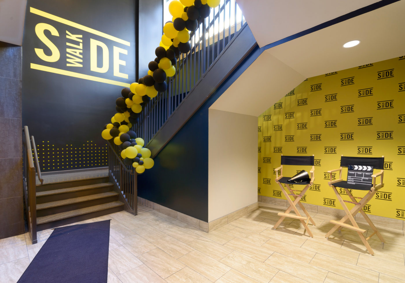 Entry area with step and repeat photo wall and branded wall graphics at Sidewalk Cinema